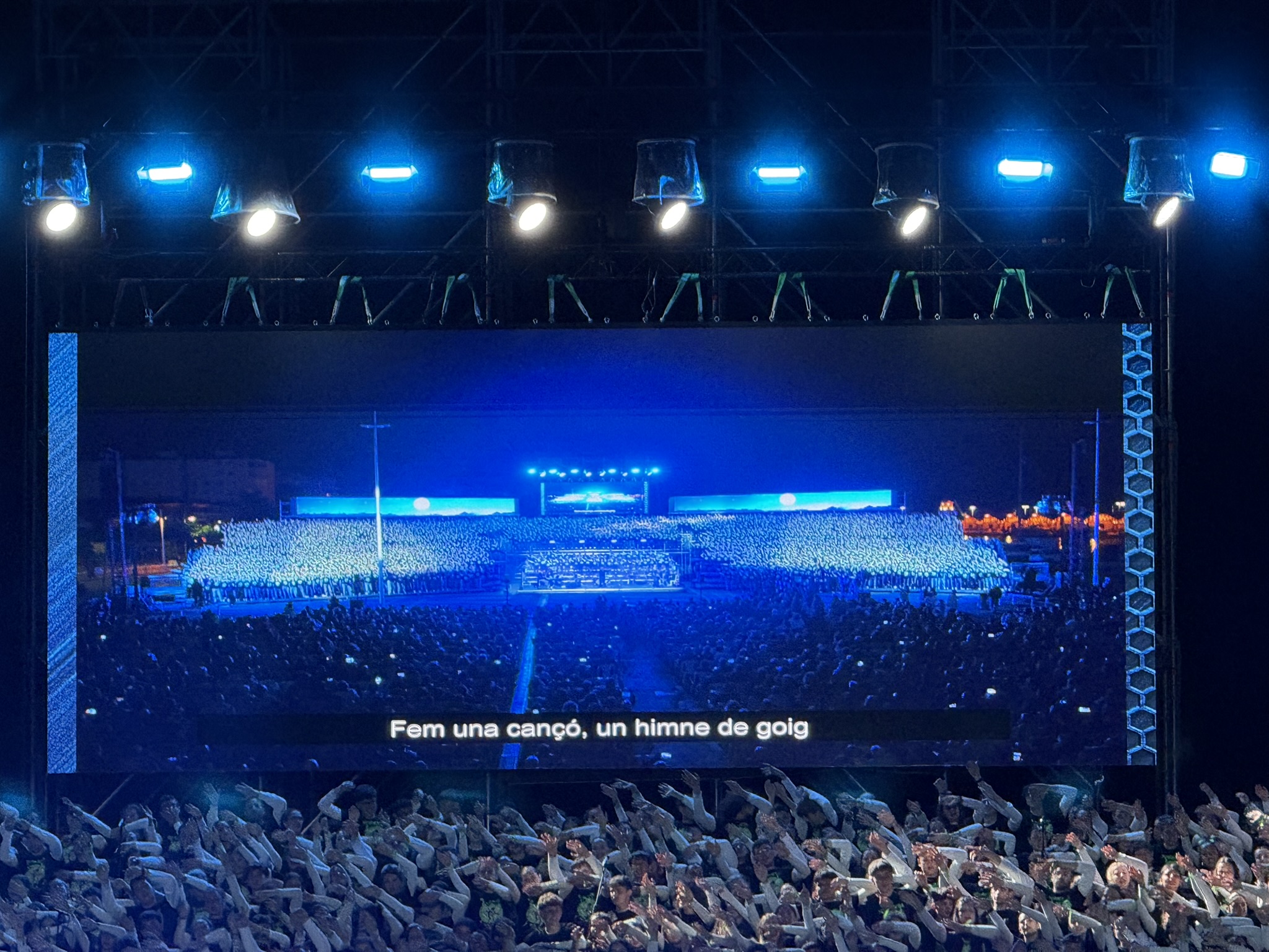 Escenario de un concierto con una gran pantalla LED, iluminación y público